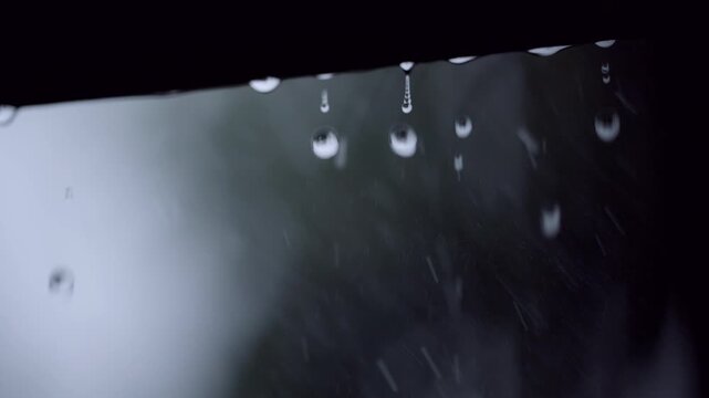 Rain Drops Falling From Roof Edge During Thunderstorm With Lightning Flash