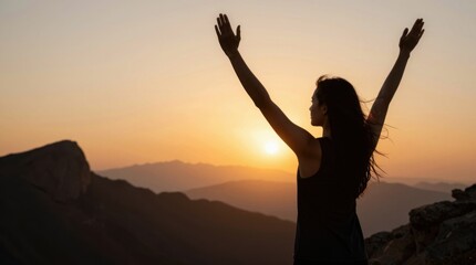 Fototapeta premium Woman raising arms watching sunset from mountain overlook during golden hour