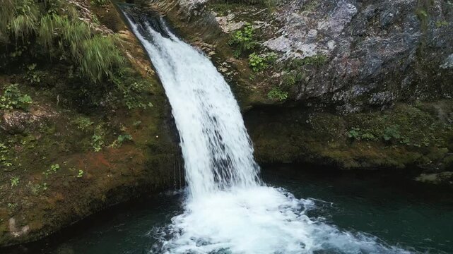 Slow motion aerial drone view of the stunning Blue Eye Kaprre waterfall and turquoise water pool in Albania. Cinematic pull-away shot.