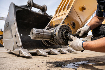 Heavy machinery mechanic performing maintenance on excavator bucket pivot joint © Snide12