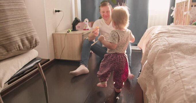 Little child practicing first steps in apartment. Everyday family life and toddler movement milestone