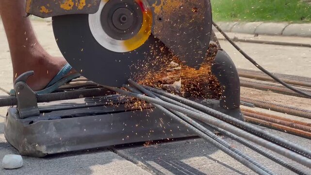 Worker Operating Electric Abrasive Chop Saw to Cut Multiple Steel Reinforcement Bars on the Ground