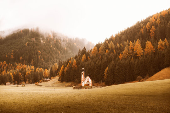 Charming church amidst autumn forest and misty hills