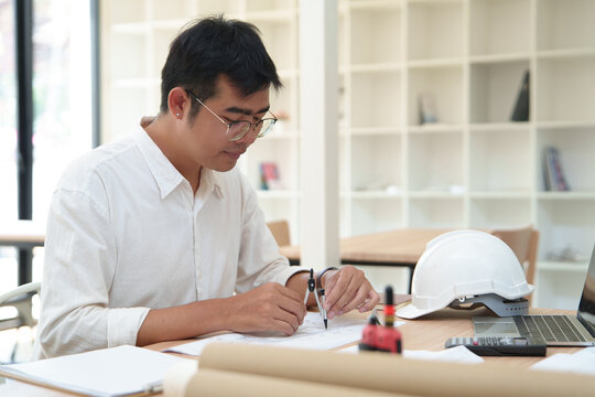 Architect working with engineering tools and plans in an office environment