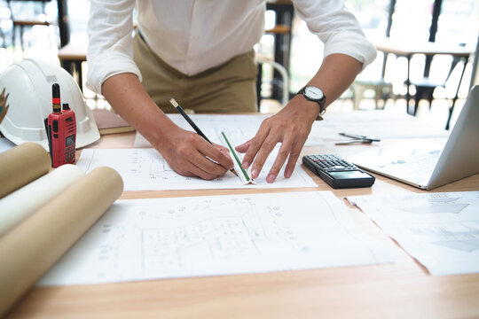 Architect or Engineer Working on Building Plans with Tools on Desk