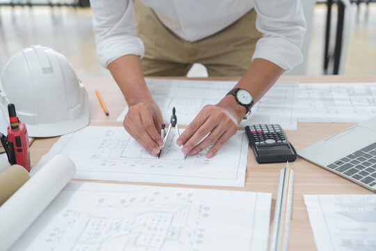 Architect or Engineer Working on Blueprint with Drawing Tools in Office Setting