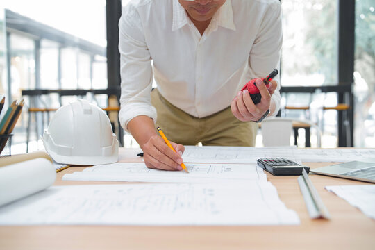 Construction professional reviewing blueprints with measuring tape and calculator