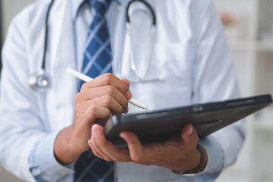 Doctor in Clinic Using Tablet for Patient Records