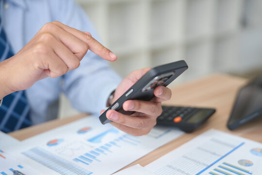 Business professional analyzing financial data on a smartphone in an office environment