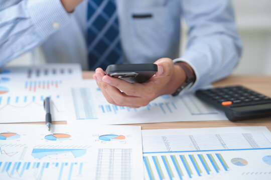 Business professional analyzing financial data with smartphone and calculator