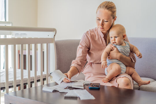 Mother sitting on sofa holding baby while calculating monthly expenses with receipts at home. Stressed mom managing budget and childcare. Financial stress, parenthood and real life concept