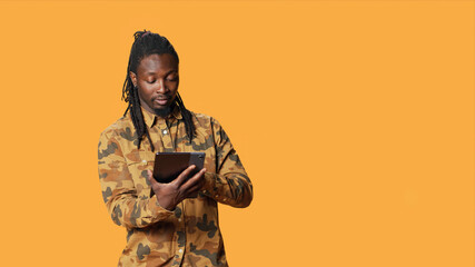 Modern person navigating online on tablet in studio, using mobile device to check social media apps and browse internet pages, with man checking websites on gadget. © DC Studio