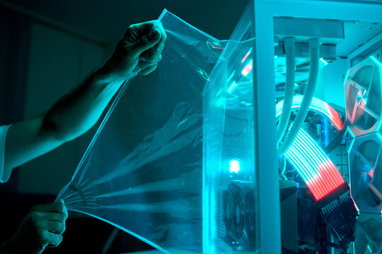 Man examining illuminated transparent computer case in dim room