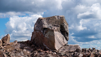Large textured granite boulder standing against a dramatic cloudy summer sky in Karelia, Russia. © Mikhail Andreev