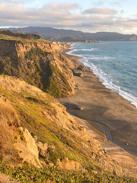 Dramatic coastal cliffs extending to the horizon along the Pacific Ocean at golden hour, Pacifica, San Francisco Bay Area, Northern California