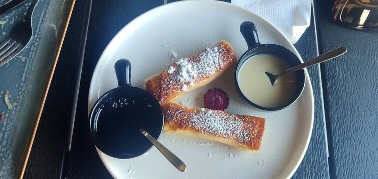 Cottage cheese filled crepes (nalysnyky) with blueberry jam and condensed milk, top view.