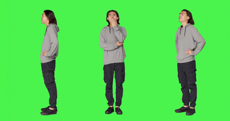 Obraz premium Young man feeling sleepy and yawning after not getting enough sleep, posing with fatigue over full body green screen backdrop, with person being extremely tired and exhausted, falling asleep.