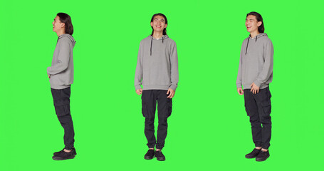 Obraz premium Cheerful male model laughing in studio, posing and being positive against full body green screen backdrop.