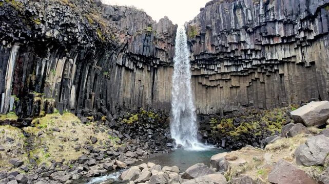 Icelandic waterfall cascading between impressive basalt columns in a volcanic landscape. Svartifoss, Vatnaj&ouml;kull National Park, Iceland
