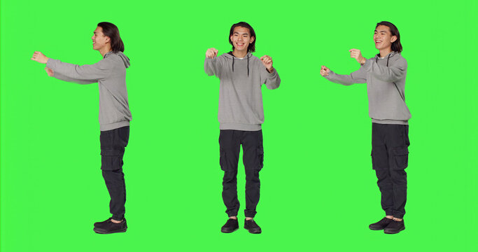 Man acting as choir director for musical show, moving hands like a choirmaster chief over green screen backdrop, with male person conducting band to sing, smiling choirmaster musician.