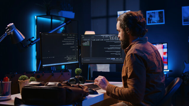 Freelancing software programmer arriving in personal office at home, resuming work on coding.