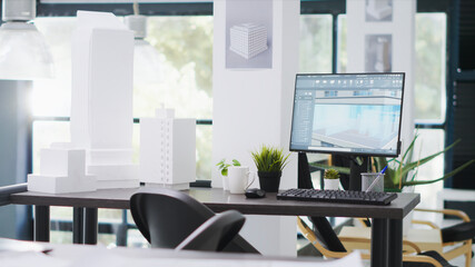 Fototapeta premium Designing office has empty desk with computer operating CAD, production layouts and blueprints on the design table, architectural work environment fitted with latest modeling appliances.