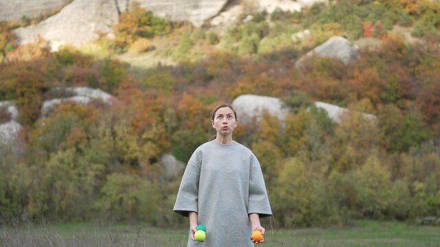 Skilled Juggling Performance Practicing Woman Throws Balls Against Autumn Mountain Backdrop