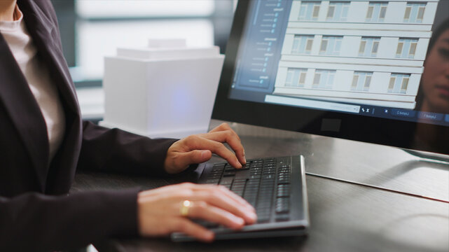 Skilled designer using 3D modeling tools to develop designs for buildings, create architectural plans at desk, woman performing engineering task with CAD software app in a startup office.
