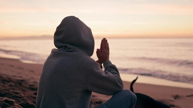 unrecognizable person meditating on a beach at sunrise. inner peace, spirituality and mindfulness in a zen lifestyle.