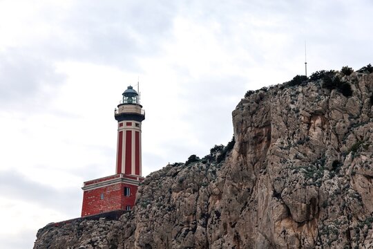 Capri, Italy - 7. March 2026: Red and white lighthouse standing on Capri island cliff
