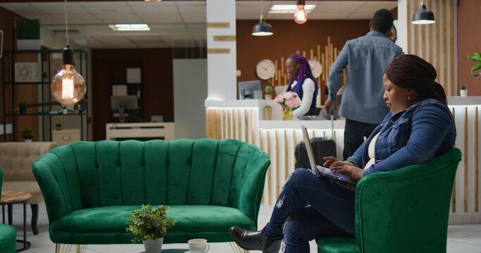 Customer checking social media webpage in lounge area, waiting for accommodation at five star hotel, young woman travelling on vacation and using laptop before room registration.