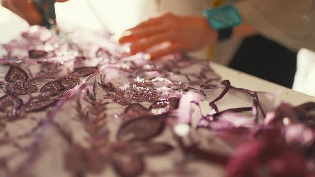 Fashion designer cutting beaded lace fabric