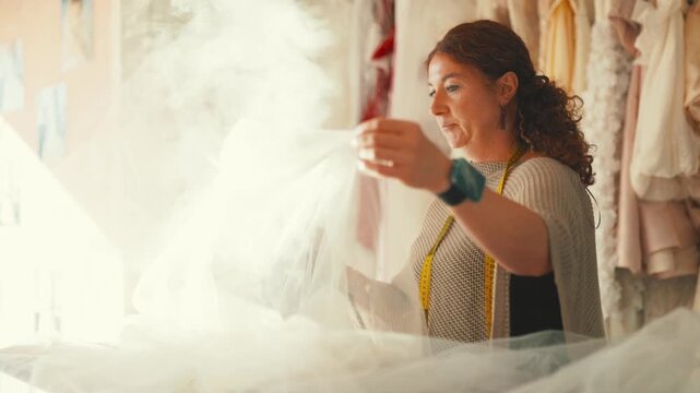 Seamstress steaming wedding dress tulle in atelier