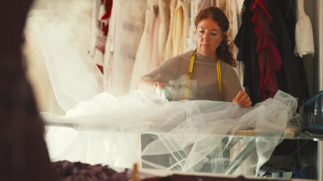 Seamstress steaming white tulle wedding dress fabric