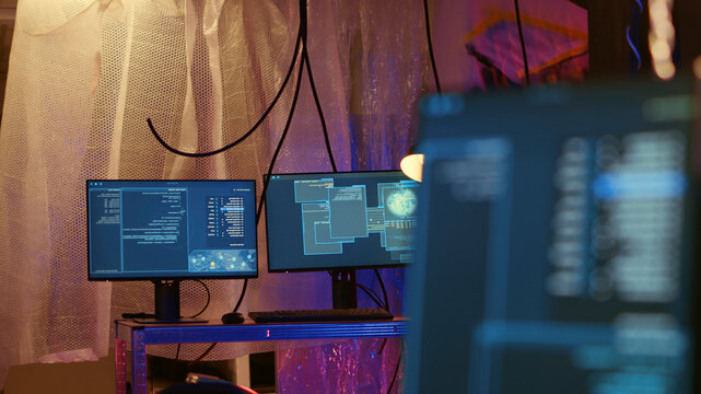 Empty abandoned underground warehouse with lines of code running on computer screen with malware that get past security systems, monitors in hidden HQ showing scripts that can hack devices.