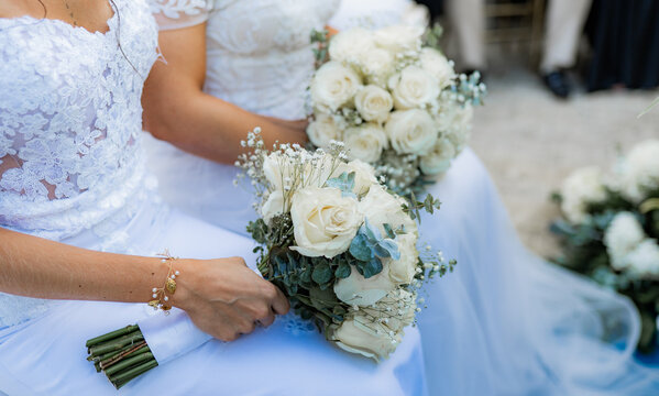 Novias con elegantes ramos de rosas blancas durante ceremonia de boda rom&aacute;ntica