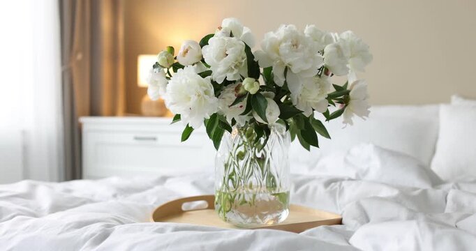 Bouquet of beautiful peony flowers on bed at home. Camera moving left