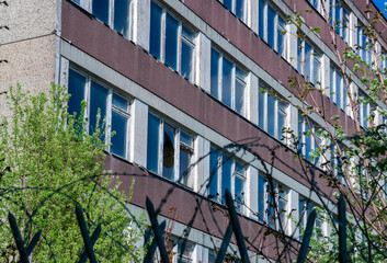 Residential building facade viewed through an out-of-focus security fence with barbed wire, creating a visual concept of separation, surveillance and urban architecture. © Timothy Shoot