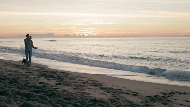 Man taking a selfie with his dog on the beach during sunrise
