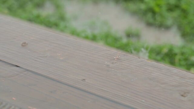 Raindrops falling on wooden stairs in summer rain, in slow motion