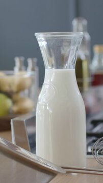 Vertical video: Starting zoom, cam focusing on milk carafe on kitchen counter for detail with sieve