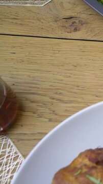 Vertical video: Sliding shot revealing roast poultry on gray tray at wood table, for dinner