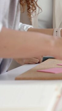 Vertical video: Placing squares on board at home, crafter with watch reacting to folded pink sheet