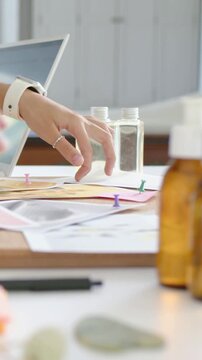 Vertical video: Entering frame right arm wearing watch sorting papers at desk, organizing pumps