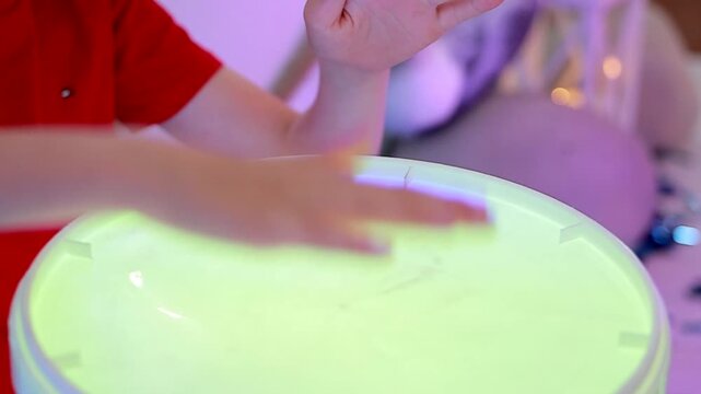 Children's hands beat on illuminated drums. Drum show. Close-up. Epic drumming performance.