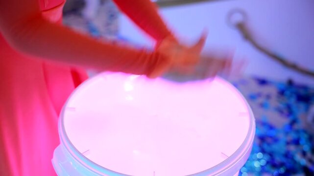 Children's hands beat on illuminated drums. Drum show. Close-up. Epic drumming performance.