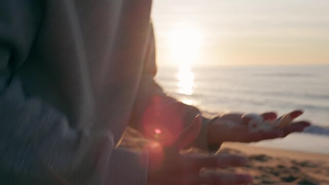 Person opening hands revealing seashells at sunrise