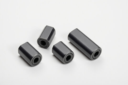 Four black ferrite core noise filters of different sizes on a clean white background, electronic components studio shot