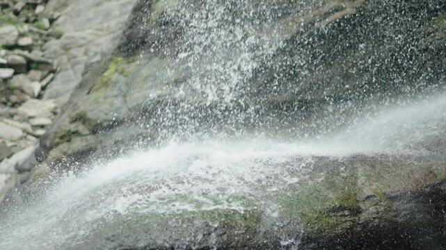 Close up of water splashing on mossy rocks from a mountain waterfall