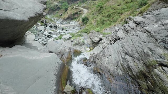 Wide angle view of a waterfall stream flowing through rocky mountain terrain